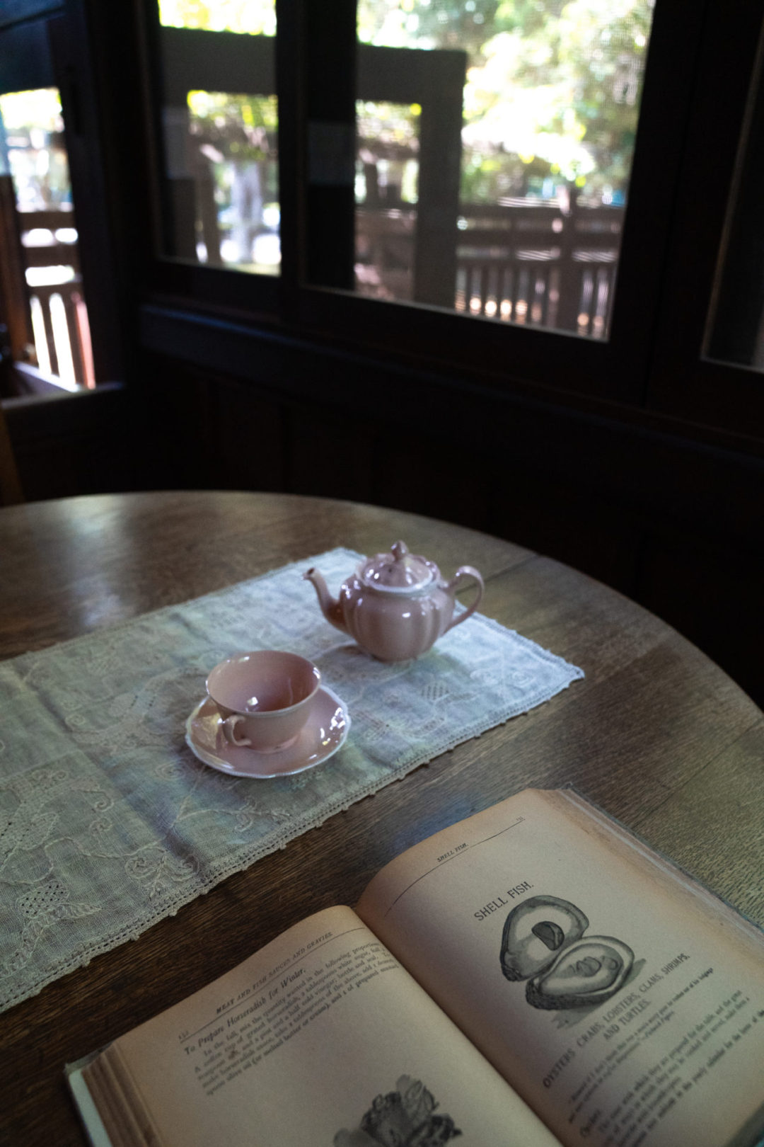 Home Tours in Los Angeles: A teapot and teacup next to an open book in the maid's dining area inside Pasadena's Gamble House