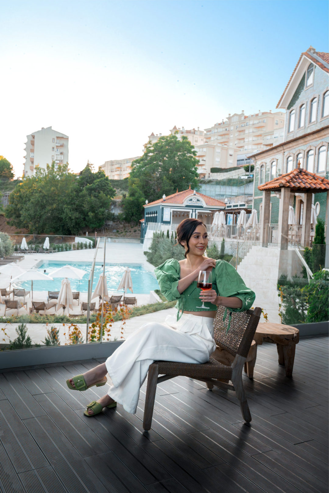 Travel Blogger Jordan Gassner sitting on a balcony overlooking the pool with a glass of wine at Lamego Hotel & Life in Portugal