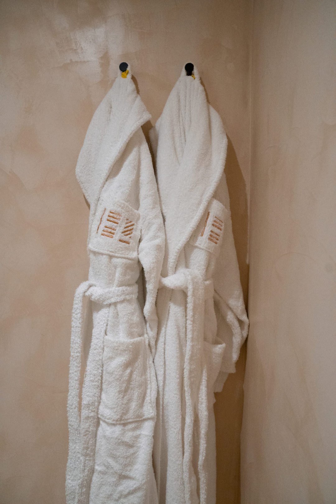 Two hotel-branded bathrobes hanging up in a guest bathroom at Lamego Hotel & Life in Portugal