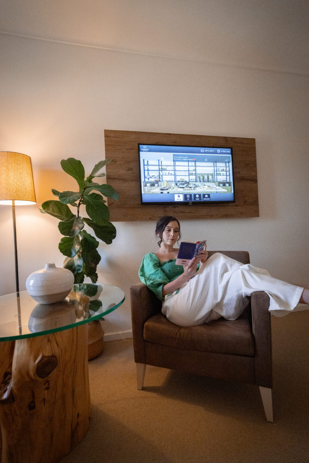 Travel Blogger Jordan Gassner reading a book while lounging on a chair in front of a flatscreen TV inside one of Lamego Hotel & Life's guestrooms