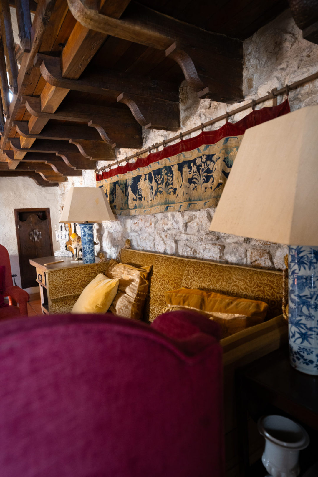 A gold and bordeaux seating area in the library of Torre De Maneys