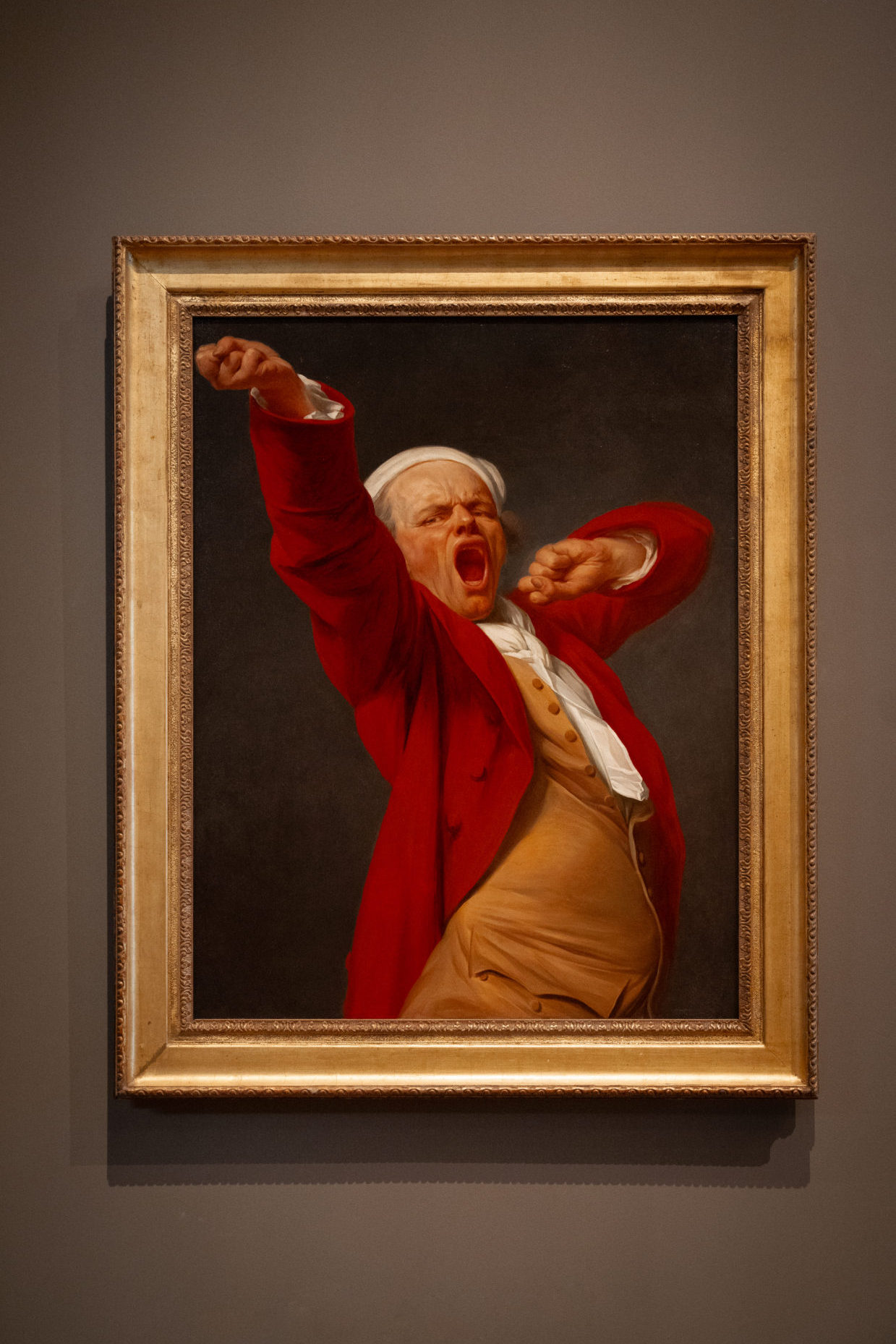 "Self Portrait, Yawning" (1783), an oil on canvas painting by Joseph Ducreux, sitting on a grey-brown wall inside The Getty in Los Angeles