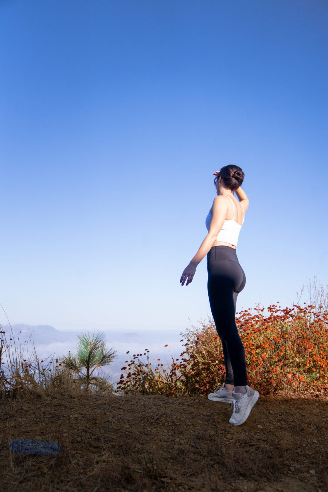 Travel Blogger Jordan Gassner shielding her eyes and looking out from a hiking viewpoint above the clouds in Topanga Canyon, California