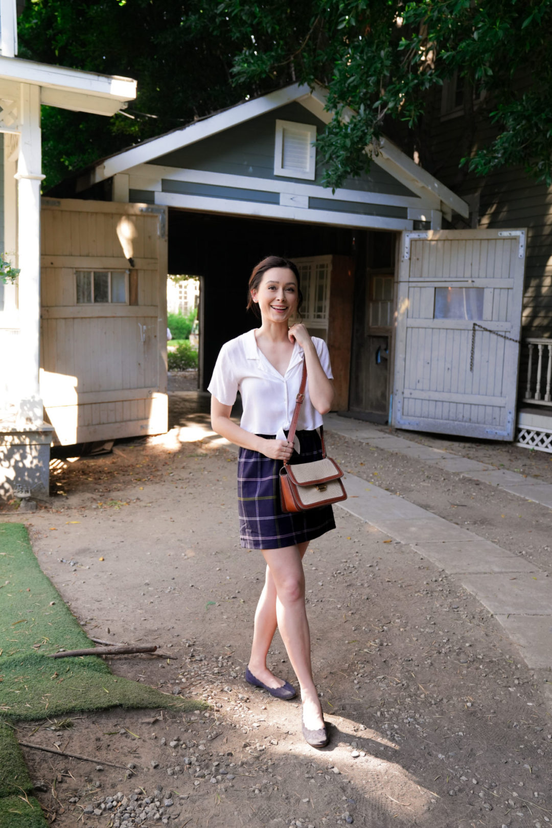 Travel Blogger Jordan Gassner smiling in front of Warner Bros Studio's famous facade that is used as Lorelai and Rory's garage from Gilmore Girls