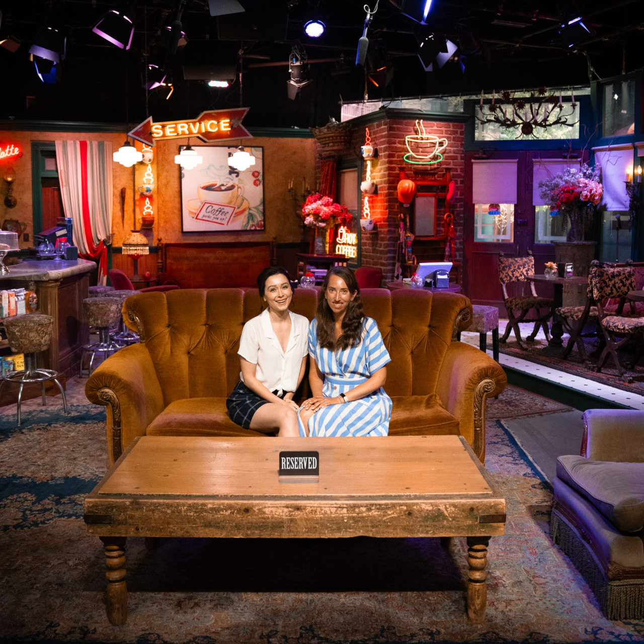 Travel Blogger Jordan Gassner and her friend, Kate, sitting on the iconic sofa inside the Central Perk Cafe set in the Warner Bros. Studio Tour