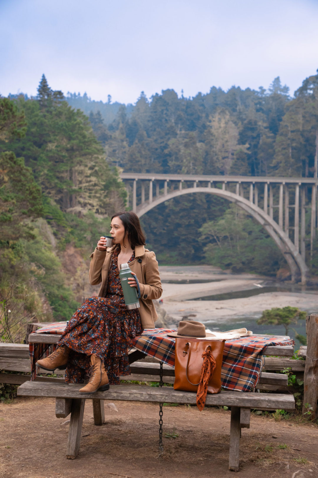 Travel Blogger Jordan Gassner drinking apple cider from a thermos in Russian Gulch State Park Bridge near the Mendocino Coast