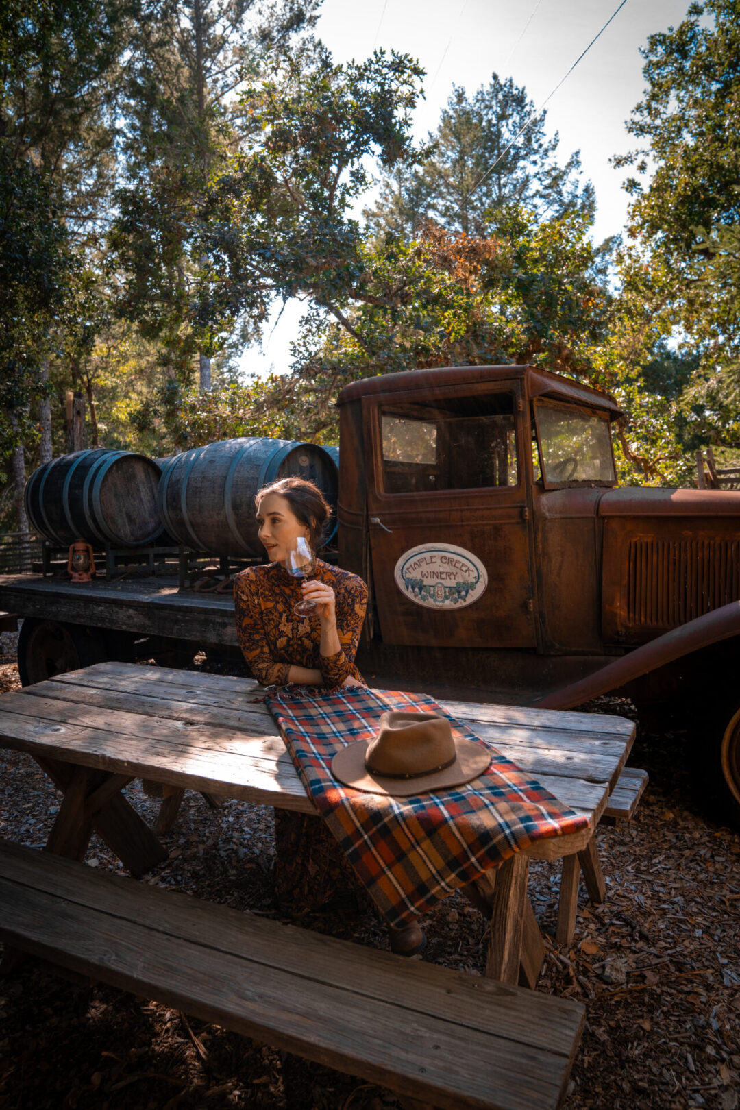Travel Blogger Jordan Gassner holding a glass of wine while seated at a picnic table at Maple Creek Winery in California's Mendocino County
