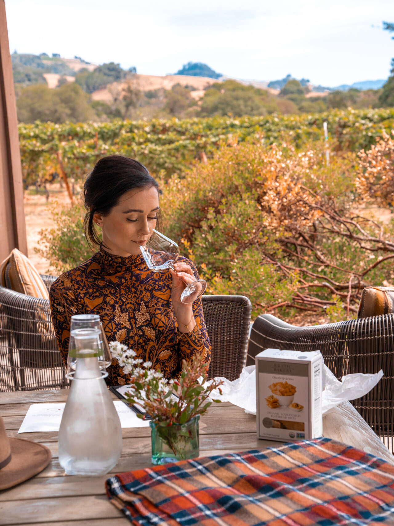 Travel Blogger Jordan Gassner smelling a glass of wine on a patio near a vineyard at Domaine Anderson Winery in Philo, California