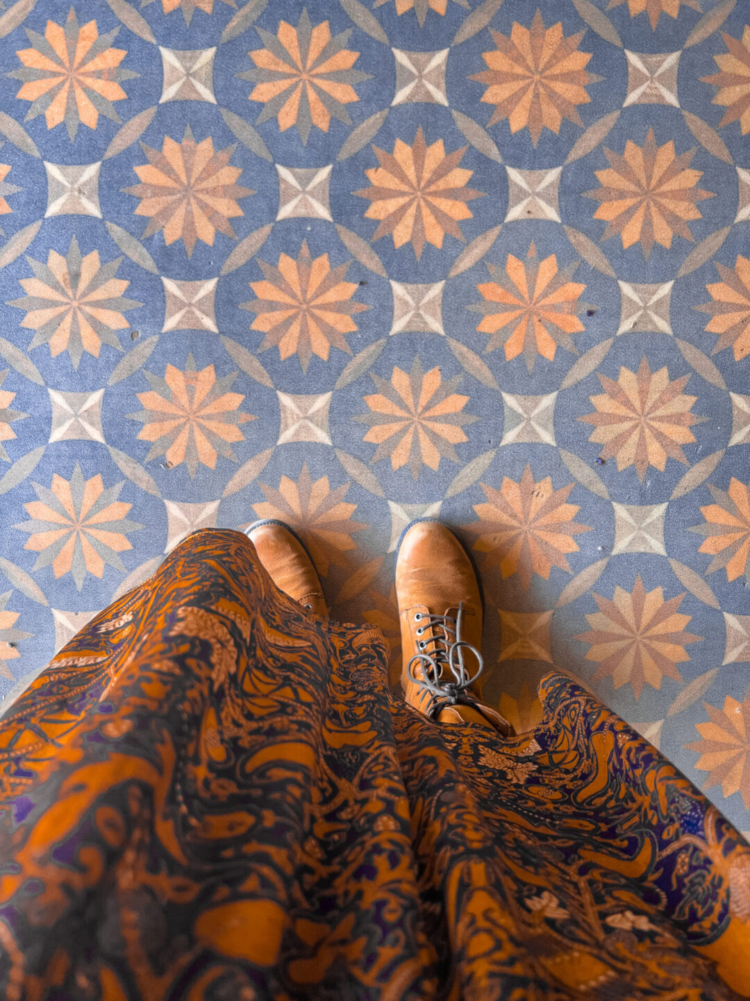 A top down view of Travel Blogger Jordan Gassner's boots standing on a colorful patterned tile floor in Farmhouse Mercantile in Boonville, California