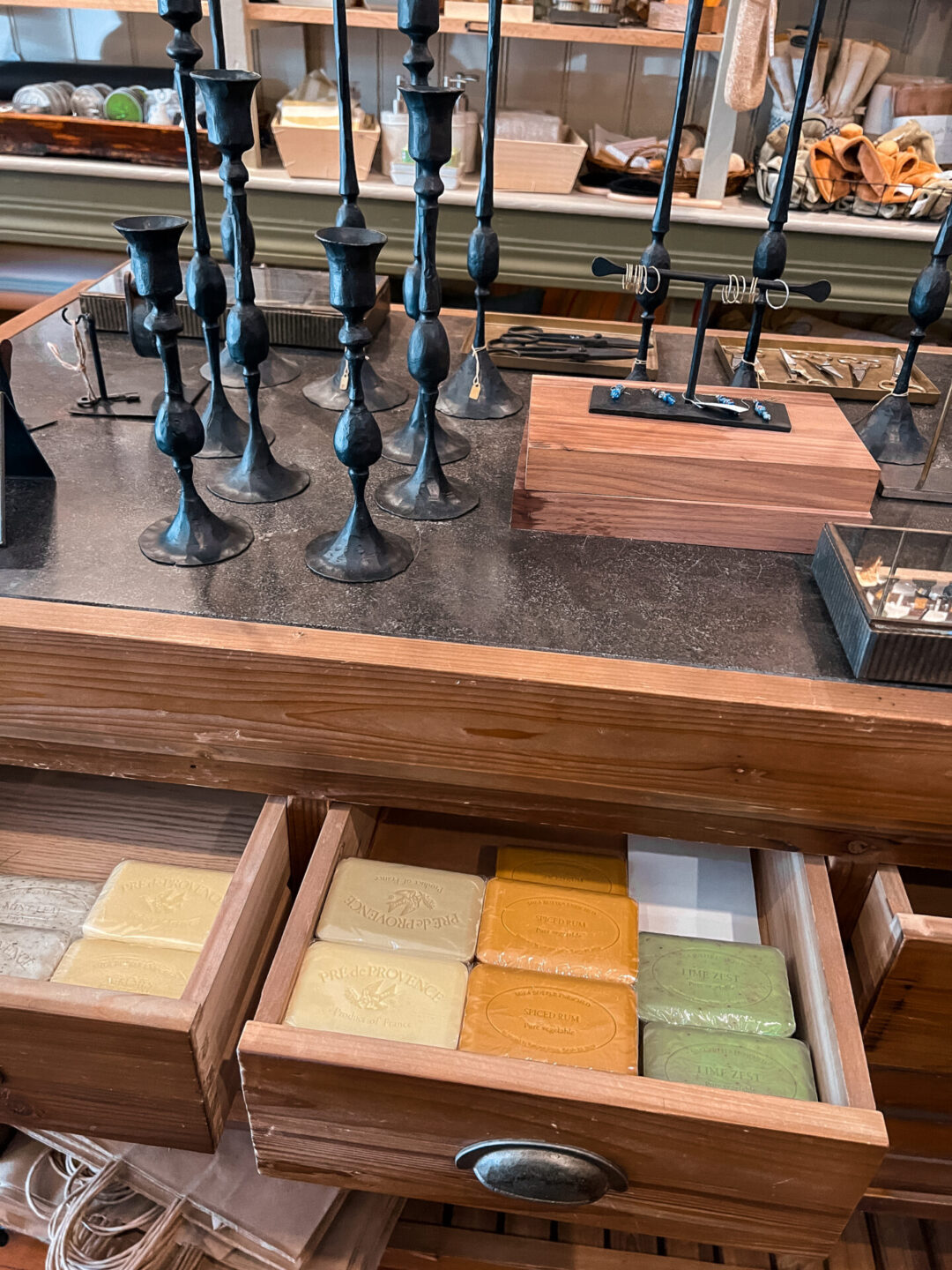 A collection of candlesticks on top of a dresser with a drawer full of artisanal soaps at Farmhouse Mercantile in Boonville, California