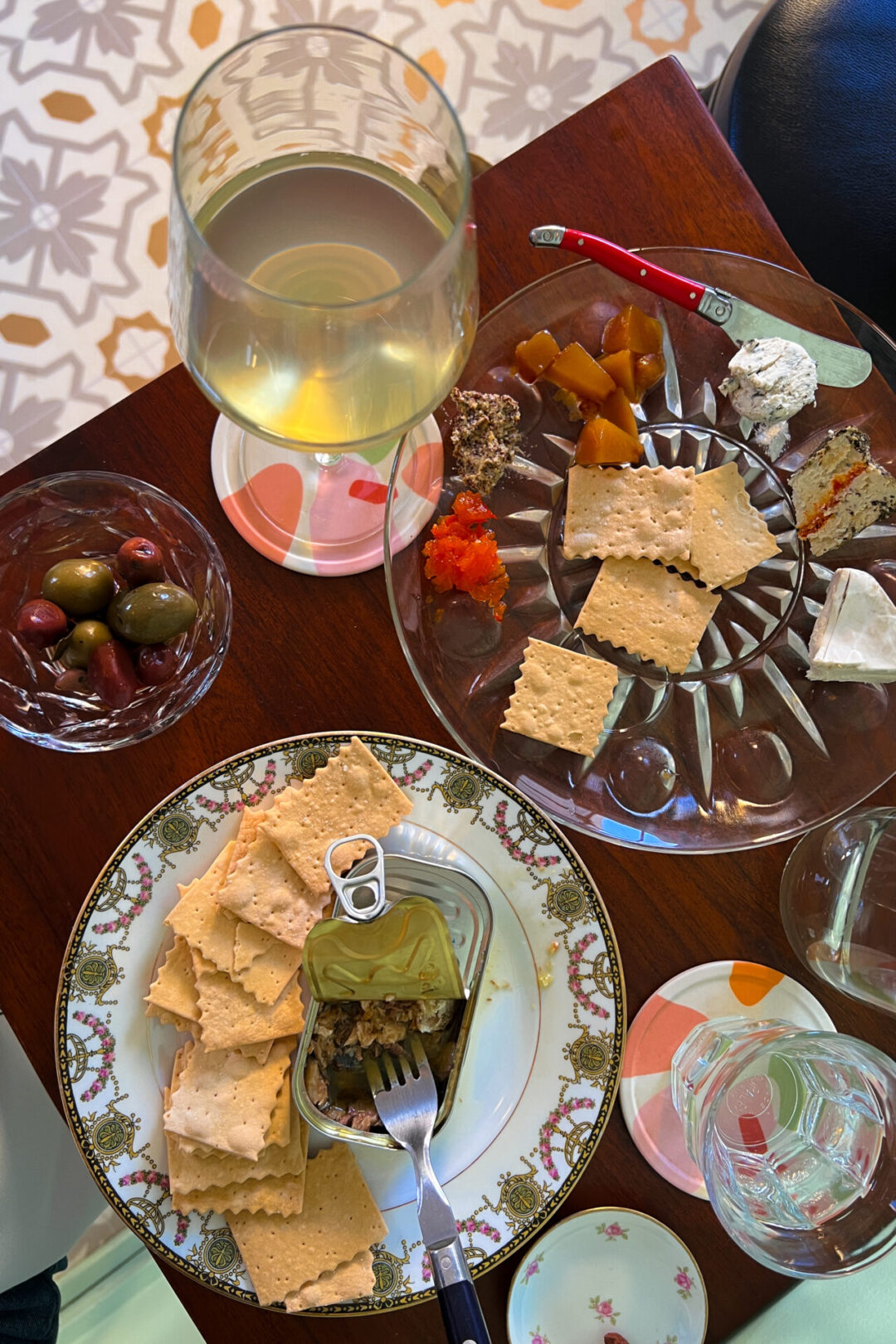 Mendocino Travel Guide: a glass of white wine, a vegan cheese plate, olives and tinned fish on a table at Fog Bottle Shop in Mendocino