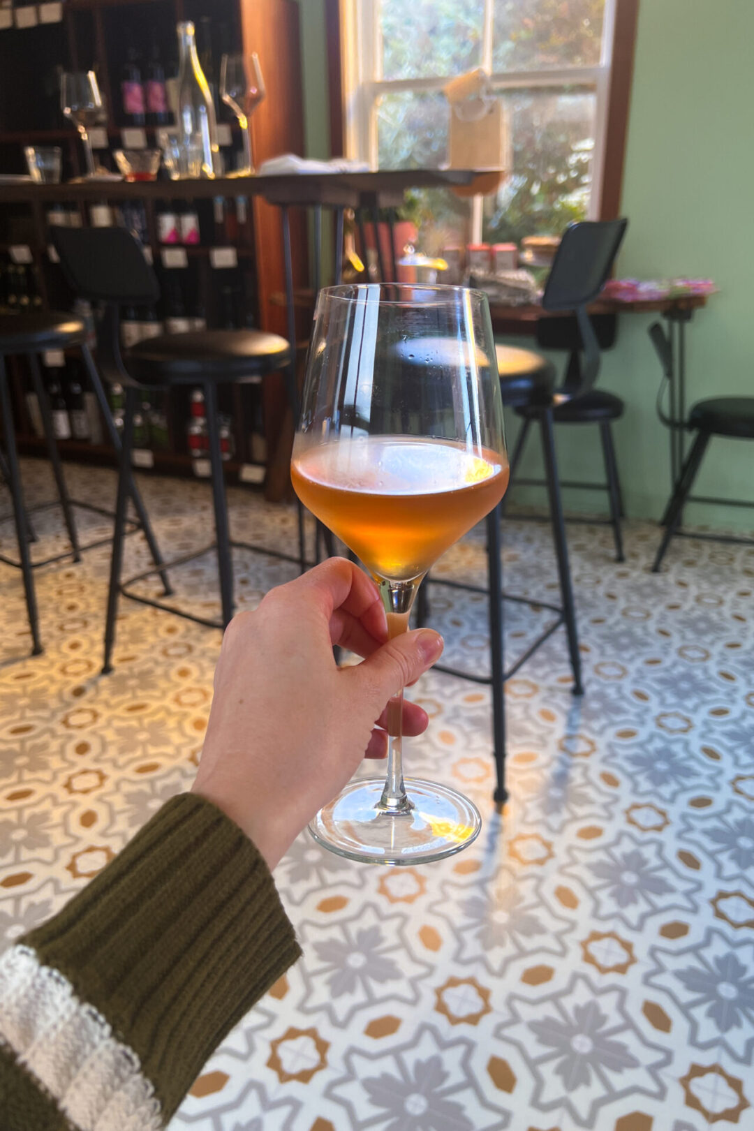 Mendocino Travel Guide: Travel Blogger Jordan Gassner holding up a glass of orange wine inside Fog Bottle Shop in Mendocino, California