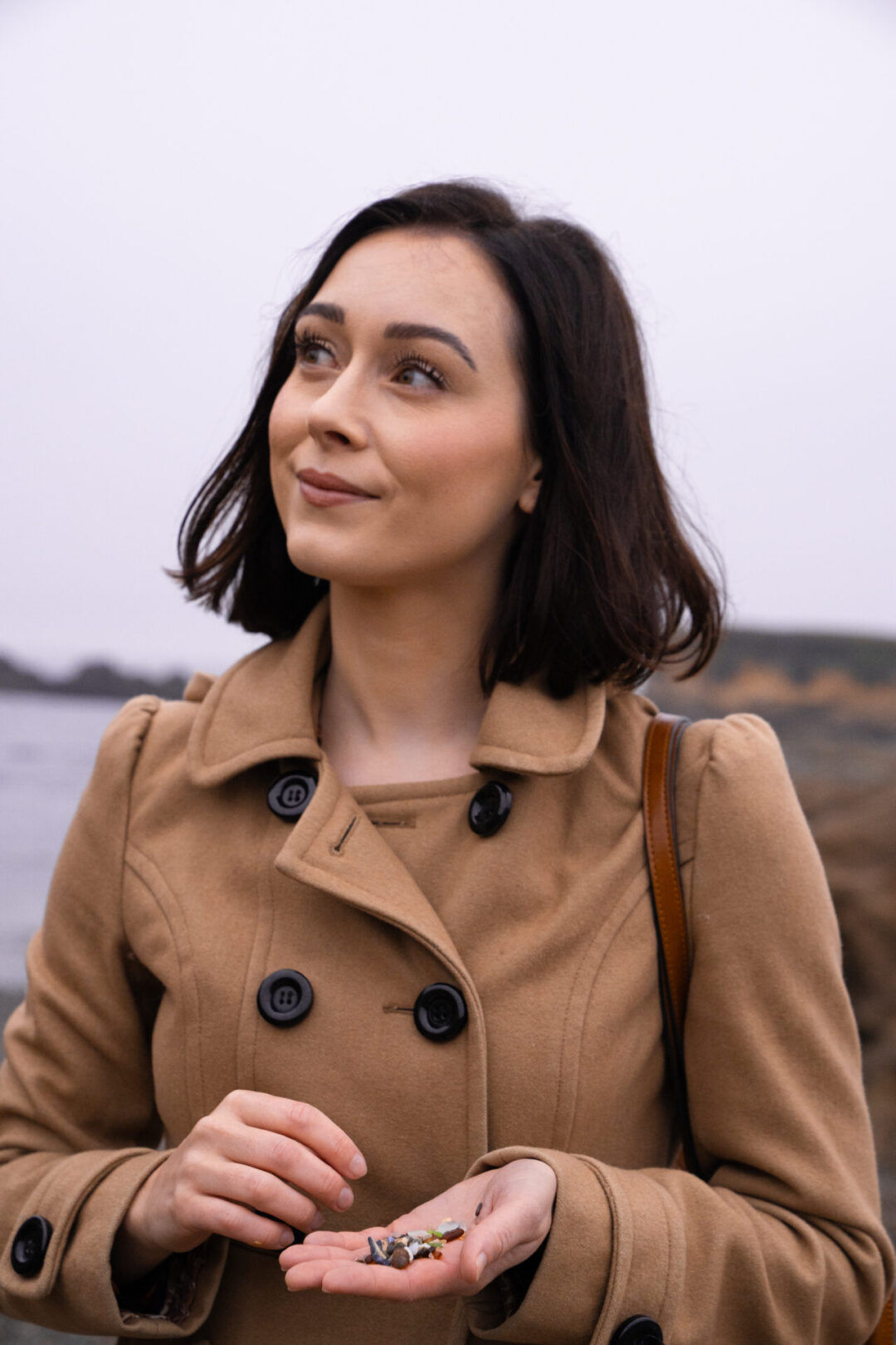 Travel Blogger Jordan Gassner looking up at the cliffs while holding some glass-sand from Glass Beach in Fort Bragg, California
