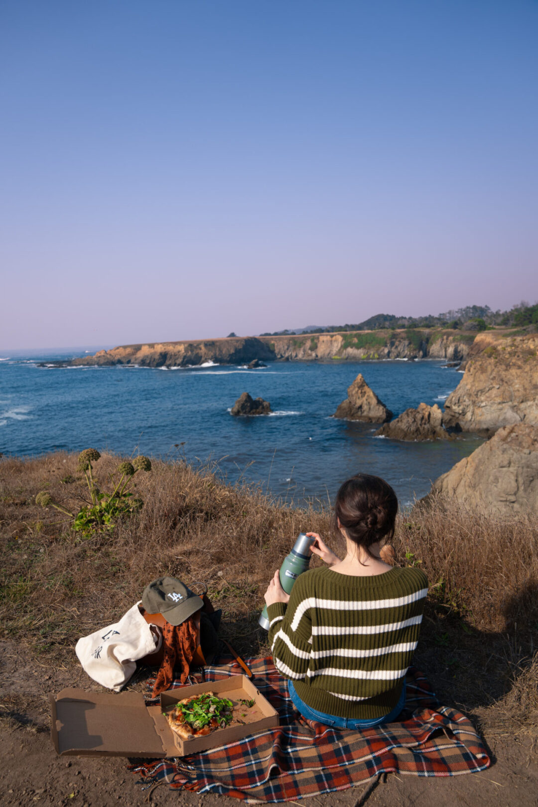 Travel Blogger Jordan Gassner putting on the cap to a Stanley thermos while on a picnic at Jug Handle State Natural Reserve near Mendocino, California
