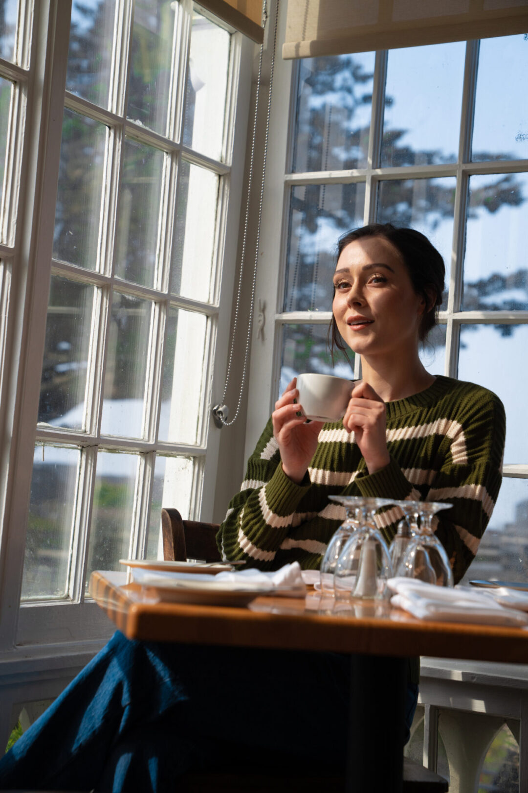 Travel Blogger Jordan Gassner enjoying a cup of tea in front of a Victorian era window inside Mendocino's MacCallum House