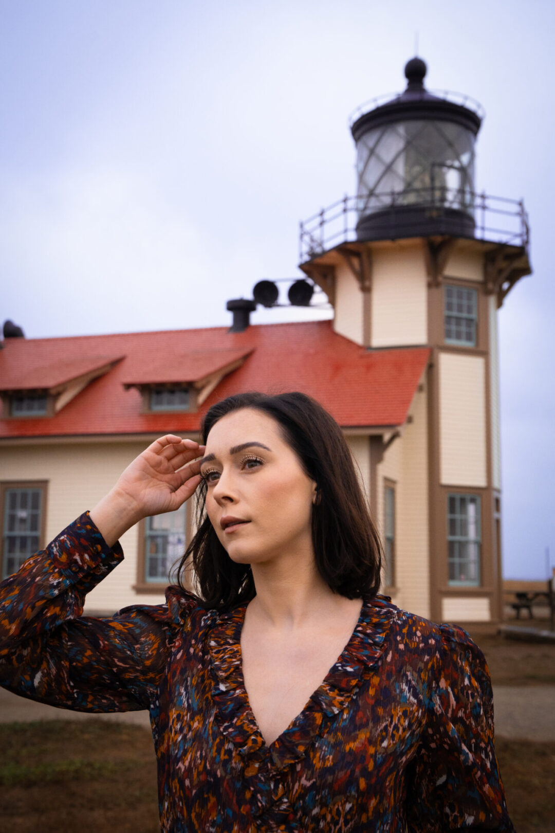 Travel Blogger Jordan Gassner moving her hair out of her face in front of Point Cabrillo Lighthouse along the Northern California coast
