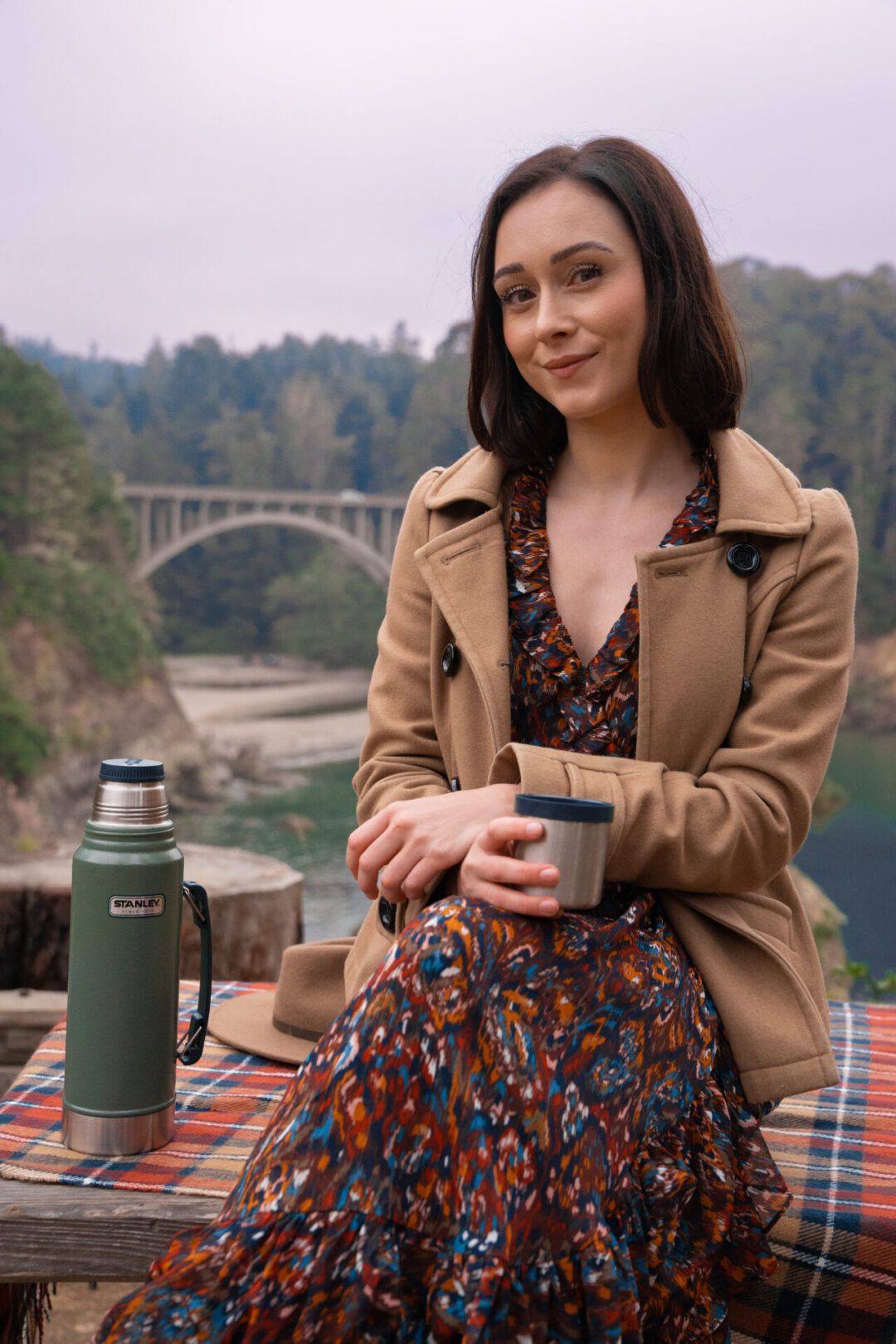 Travel Blogger Jordan Gassner smiling while sitting on a bench overlooking the Russian Gulch State Park Bridge near the Mendocino Coast in California, USA