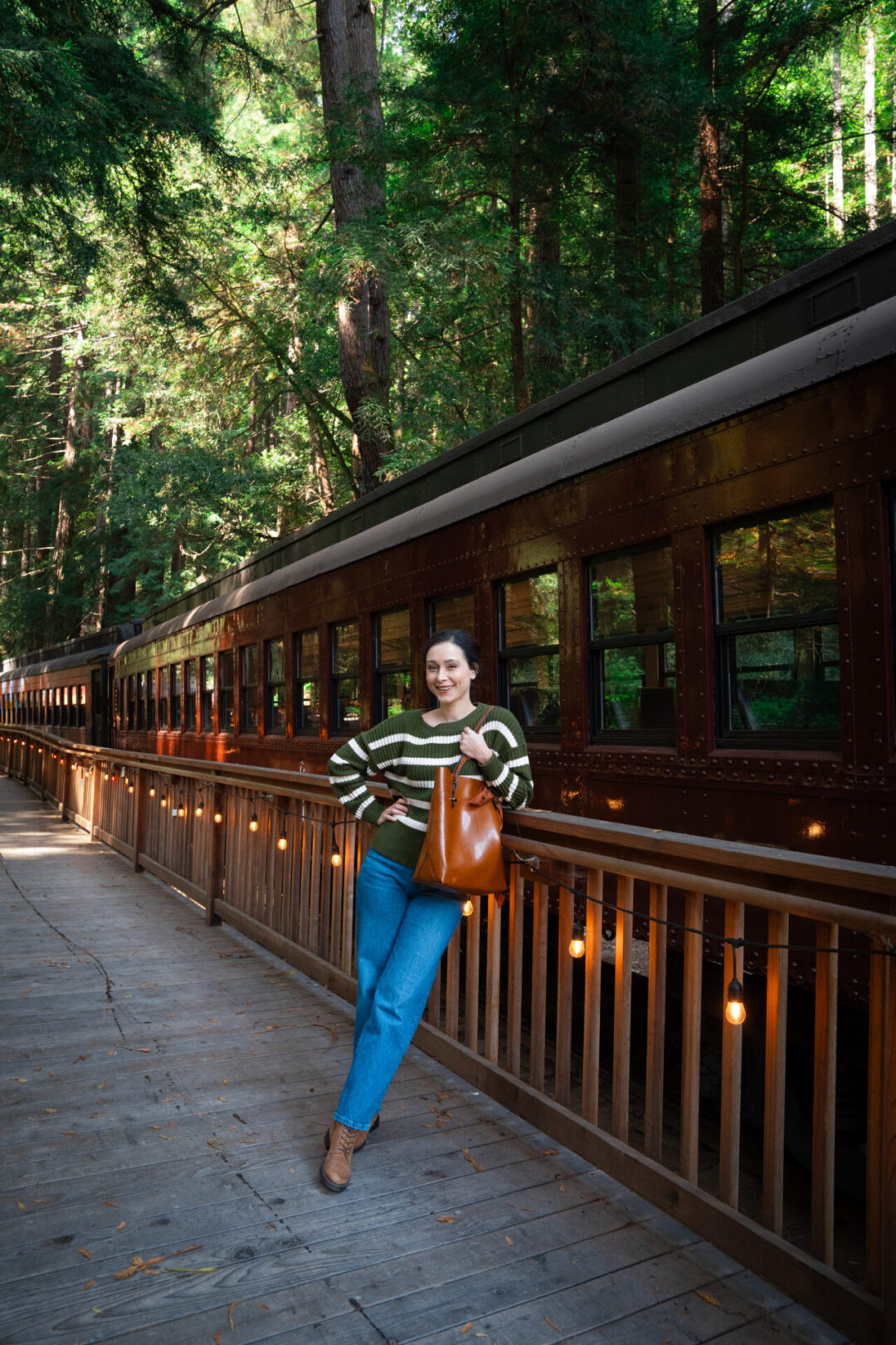 Travel Blogger Jordan Gassner smiling while leaning against the Skunk Train platform at Glen Blair Bar in Fort Bragg, California