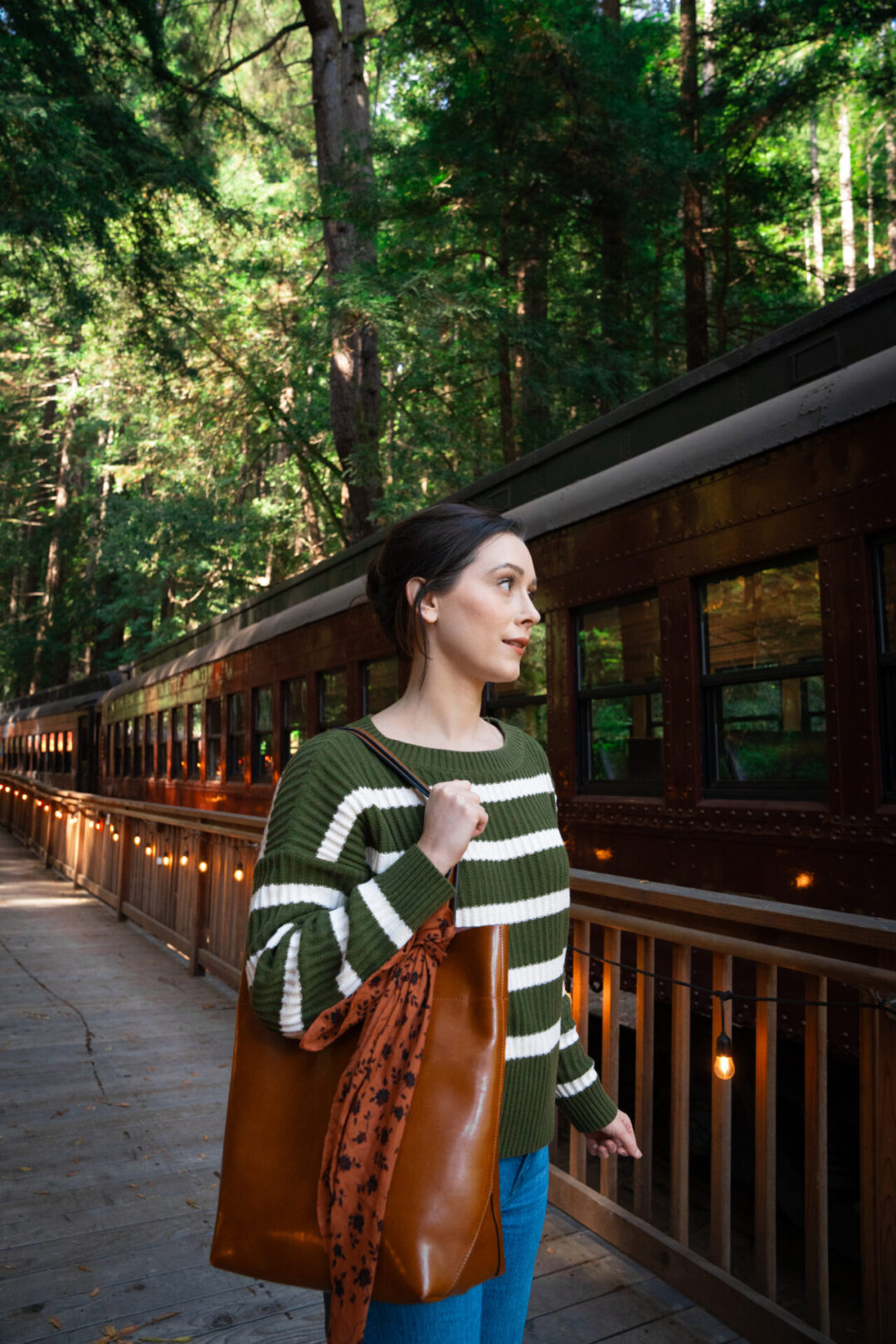 Travel Blogger Jordan Gassner holding a large brown purse on the train platform at Glen Blair Bar in Fort Bragg, California