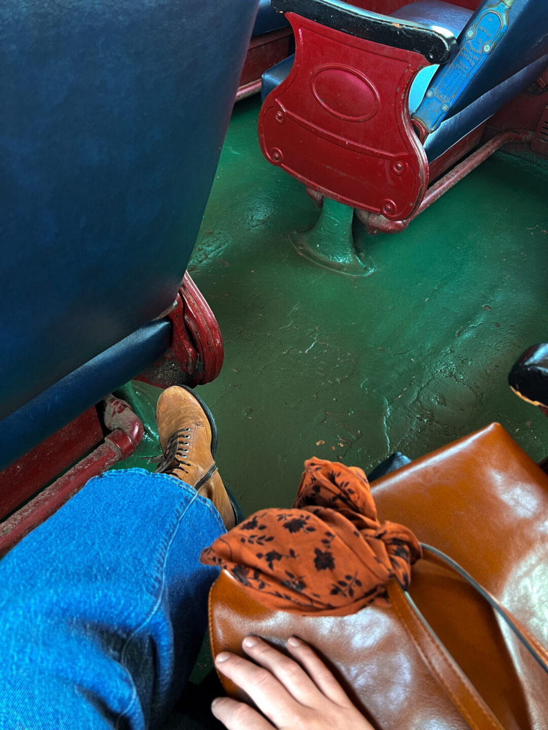 A 1st person perspective, high-angle view of a woman's purse, hand, pants and shoes while aboard the Skunk Train in Fort Bragg, California