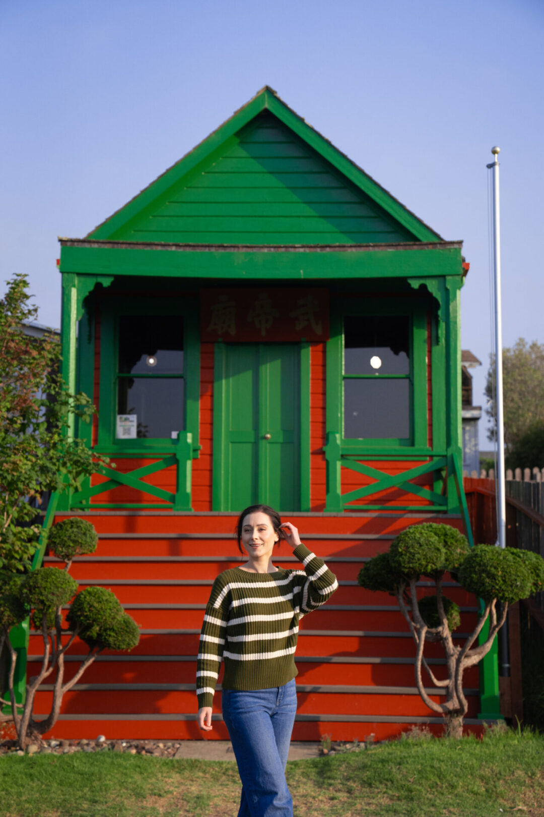 Travel Blogger Jordan Gassner smiling in front of the green and red painted Temple of Kwan Tai in Mendocino, California