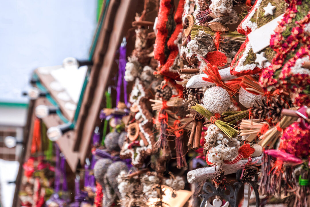 Holiday wreaths hanging from the tops of Christmas market stall kiosks.