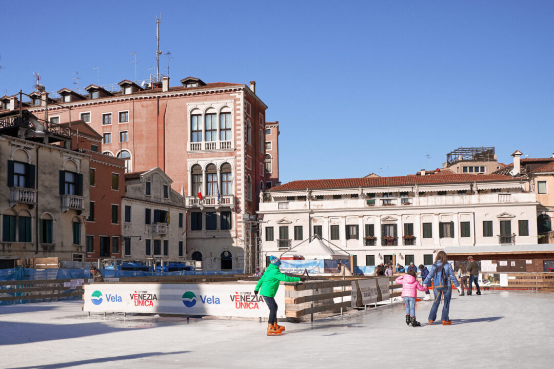 Families ice skating on an outdoor rink in the middle of Campo San Polo during the winter in Venice, Italy
