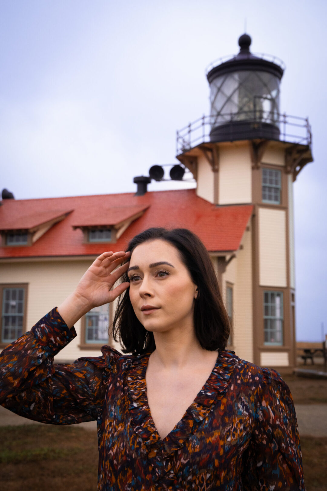 Travel Blogger Jordan Gassner moving her hair from her eyes in front of the Point Cabrillo Light Station along the Northern California coast