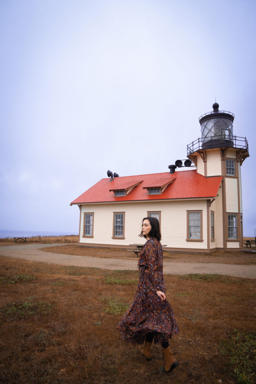 Travel Blogger Jordan Gassner looking over her shoulder in front of the Point Cabrillo Light Station along the Northern California coast