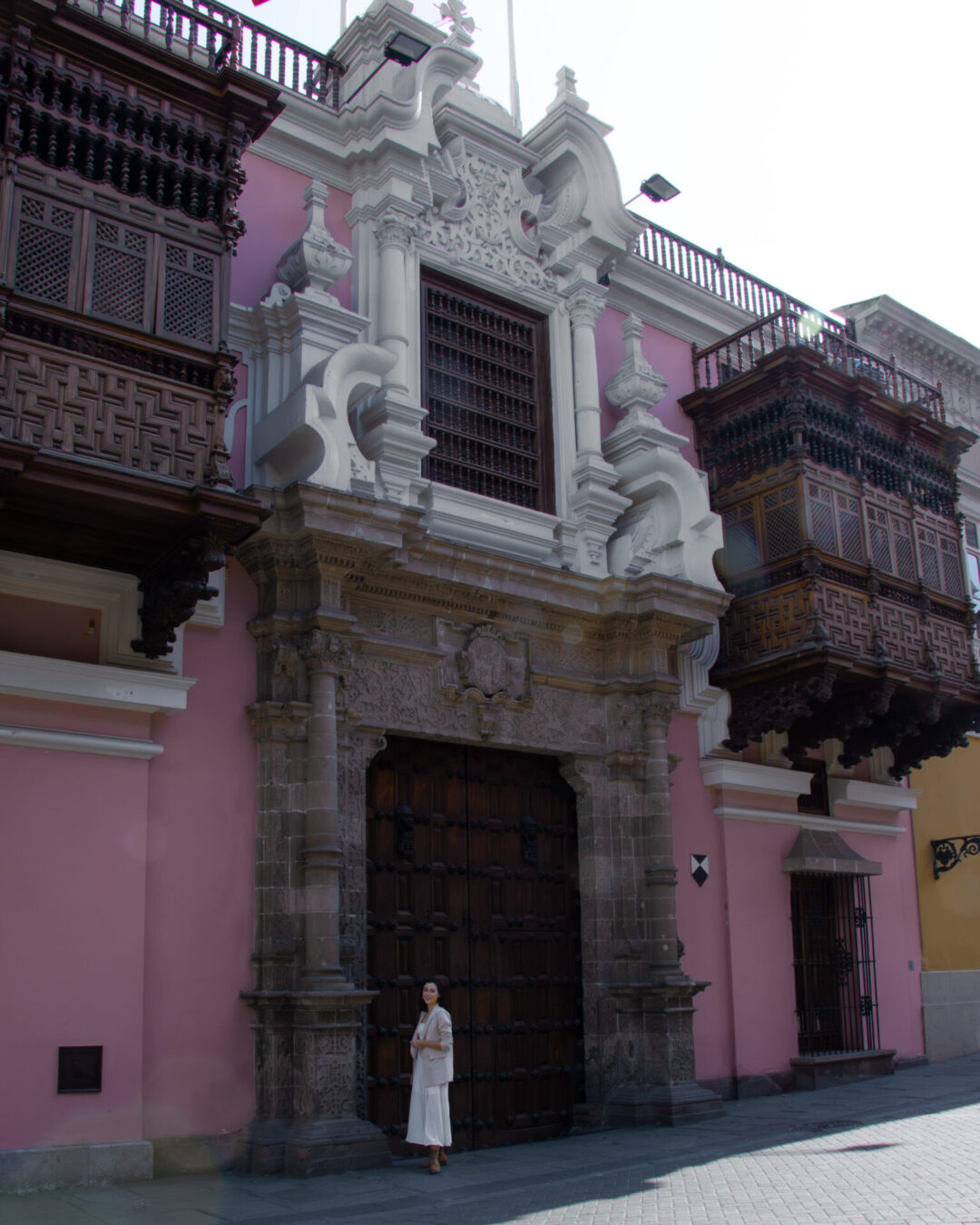 Travel Blogger Jordan Gassner standing outside the pink facade of Torre Tagle in Lima, Peru