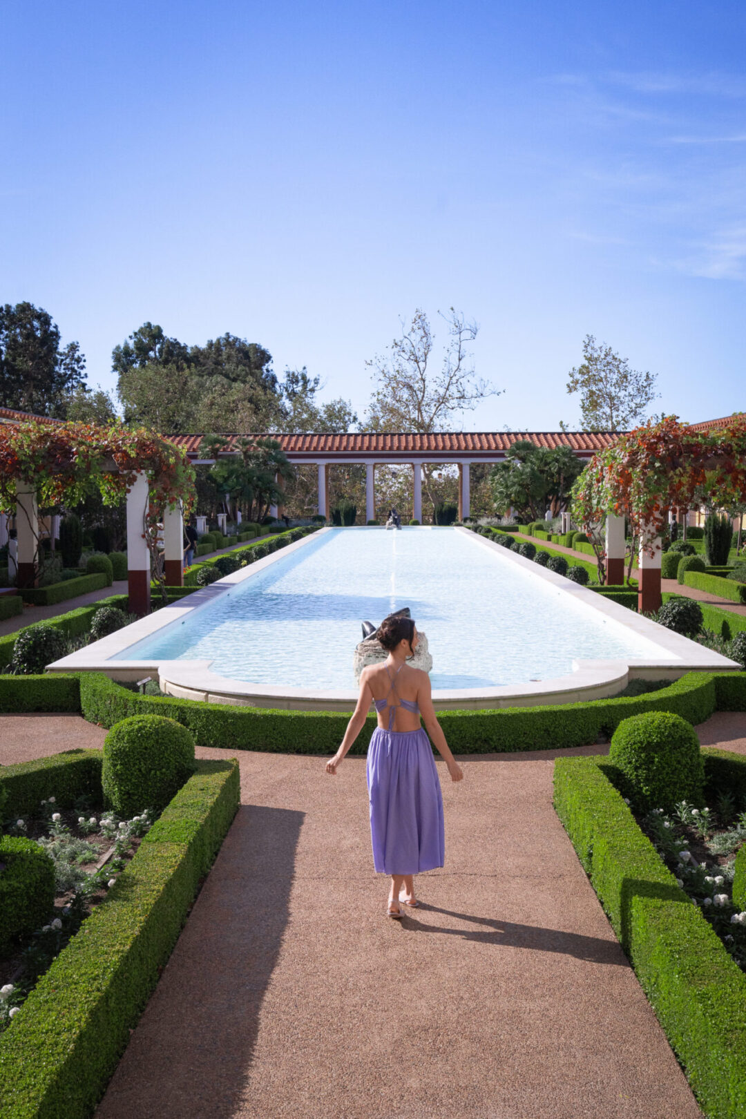 Travel Blogger Jordan Gassner walking toward the fountain in the center of the The Getty Villa gardens in Los Angeles, California