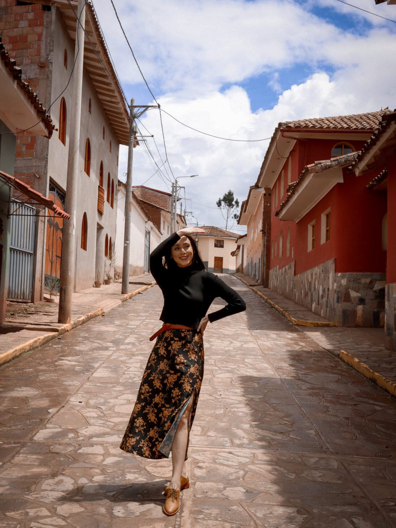 Travel Blogger Jordan Gassner shielding her eyes from the sun along a colorful street in Chichero, Peru