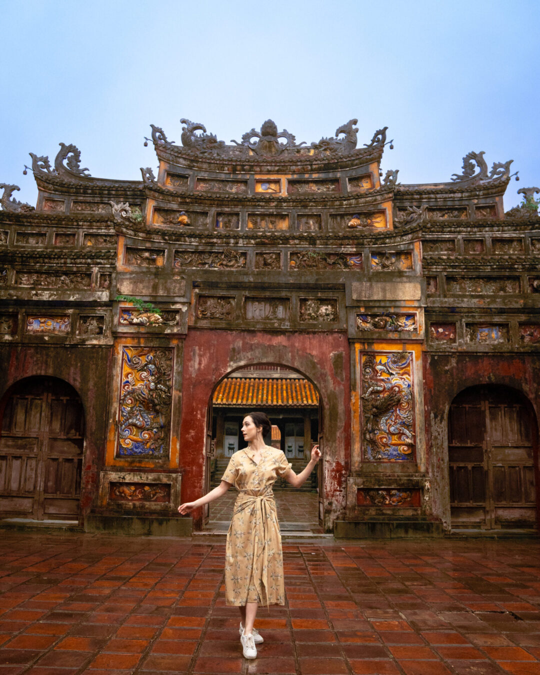 Travel Blogger Jordan Gassner standing in front of a red, yellow and blue archway inside the Imperial Citadel of Hue in Vietnam