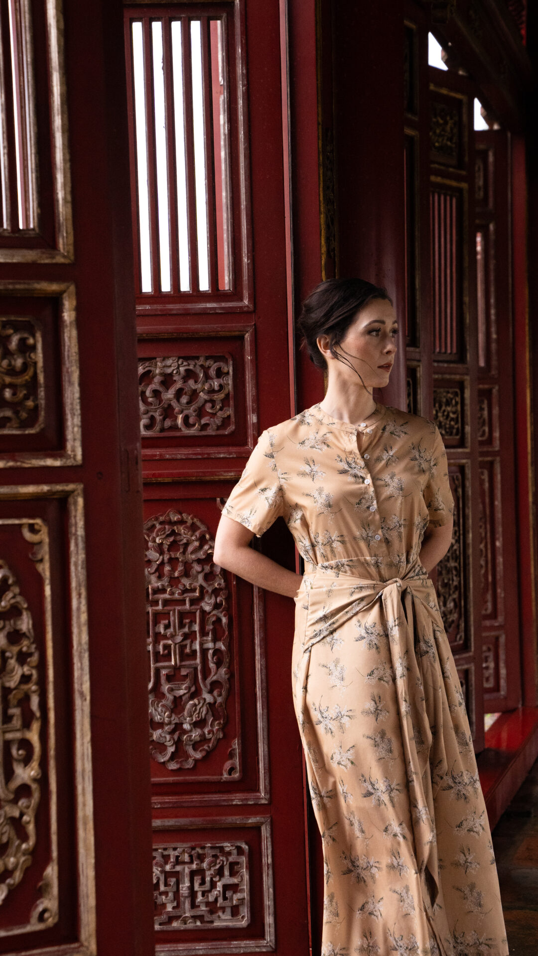 Travel Blogger Jordan Gassner leaning against a vibrant red doorway in the Imperial City Hue, Vietnam