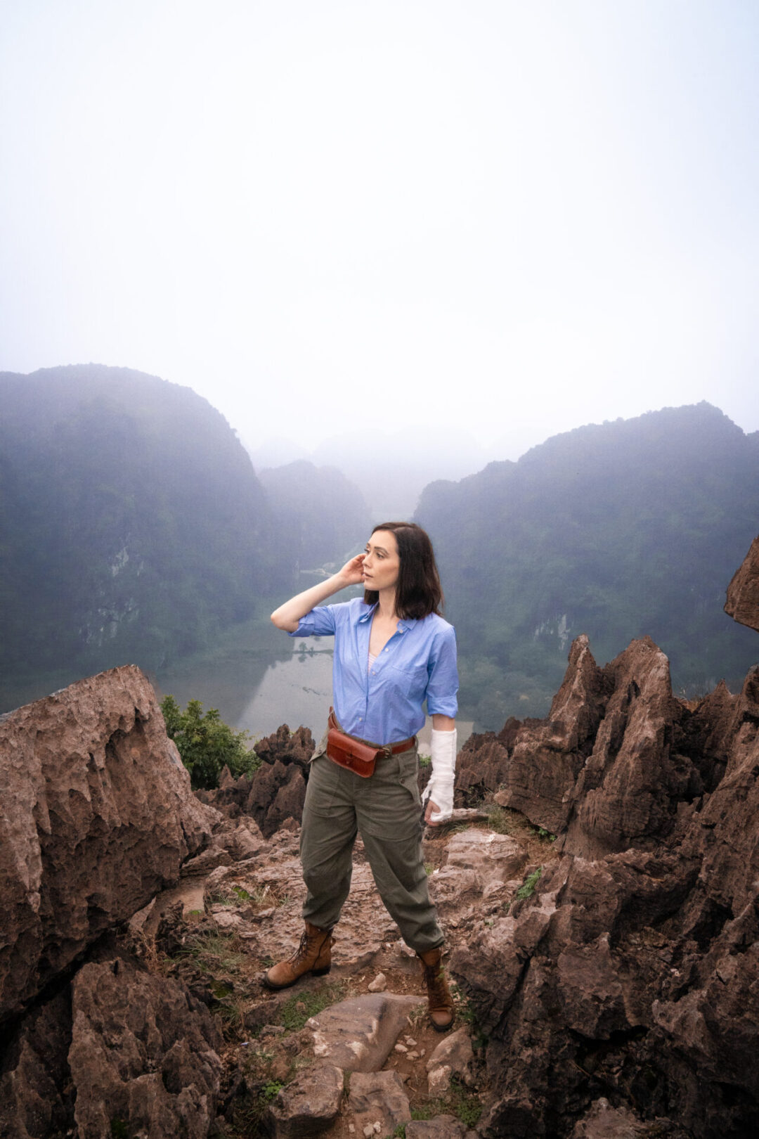 Travel Blogger Jordan Gassner looking out from the cliffs of Lying Dragon Mountain and dressed as an explorer while adventuring in Vietnam