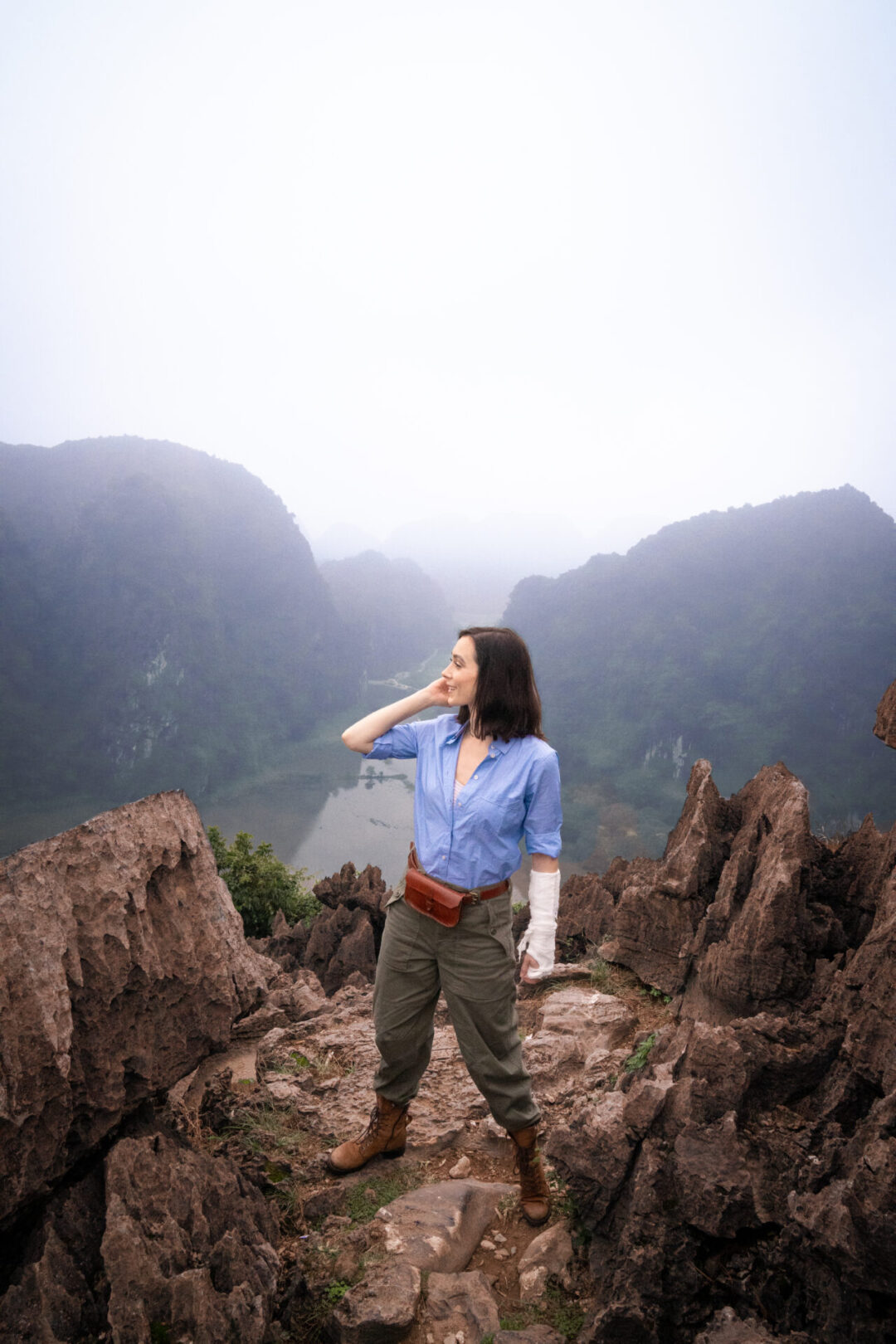 Travel Blogger Jordan Gassner standing on the cliffside of Lying Dragon Mountain and dressed as an explorer while adventuring in Vietnam