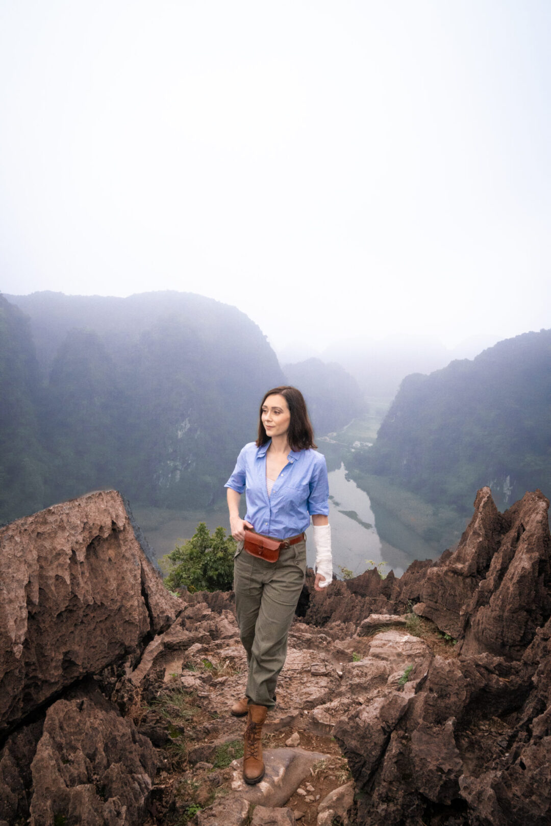 Travel Blogger Jordan Gassner adjusting her belt bag on top of Lying Dragon Mountain in Vietnam