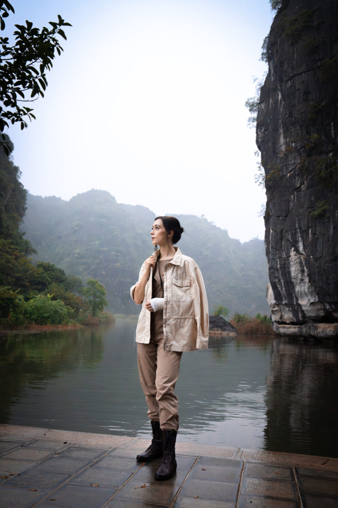 Travel Blogger Jordan Gassner bundled up in a rain-resistant jacket near the river on a misty morning in Ninh Binh, Vietnam