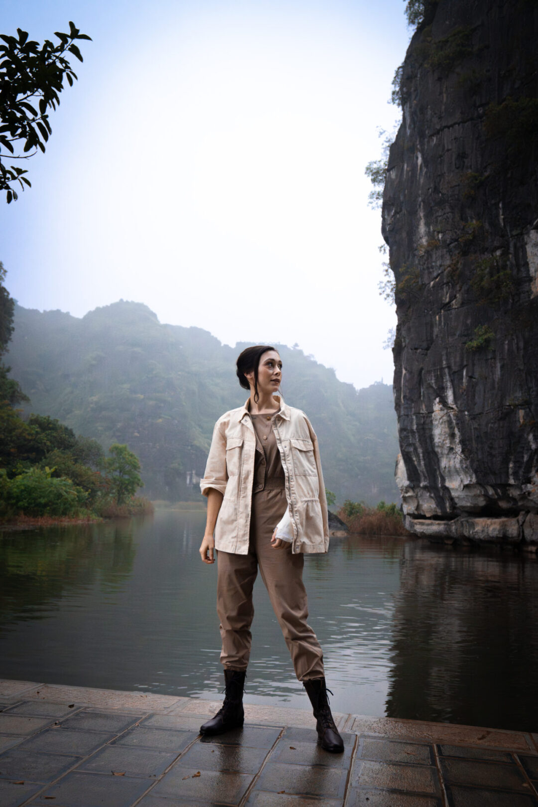 What to Pack For Vietnam: Travel Blogger Jordan Gassner standing in a Amelia Earheart inspired outfit near the river on a misty morning in Ninh Binh, Vietnam