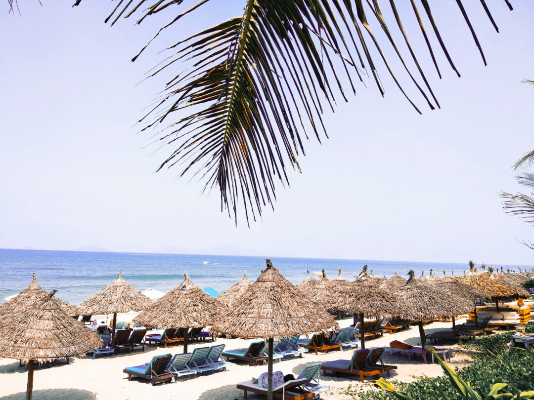 A group of straw umbrellas and loungers on An Bang Beach in Hoi An, Vietnam