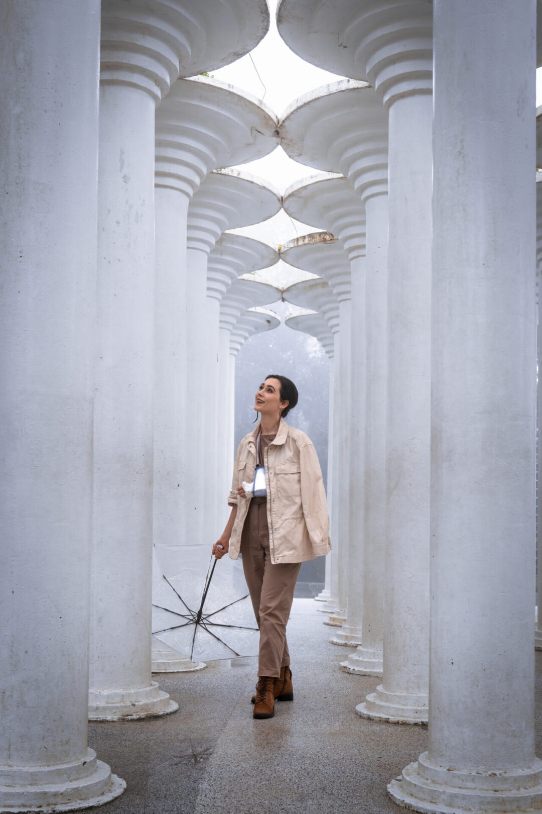 Travel Blogger smiling and holding an umbrella in a "Greek" colonnade inside a garden at SunWorld Ba Na Hills
