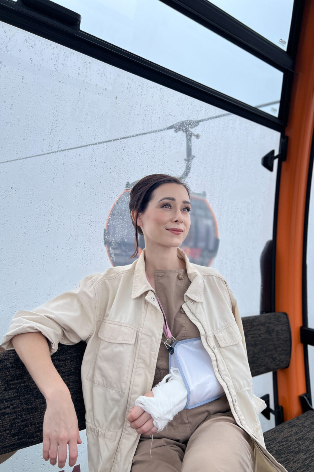 Travel Blogger smiling with her arm in a sling while sitting inside a cable car on the longest non-stop single cable car track in the world at SunWorld Ba Na Hills