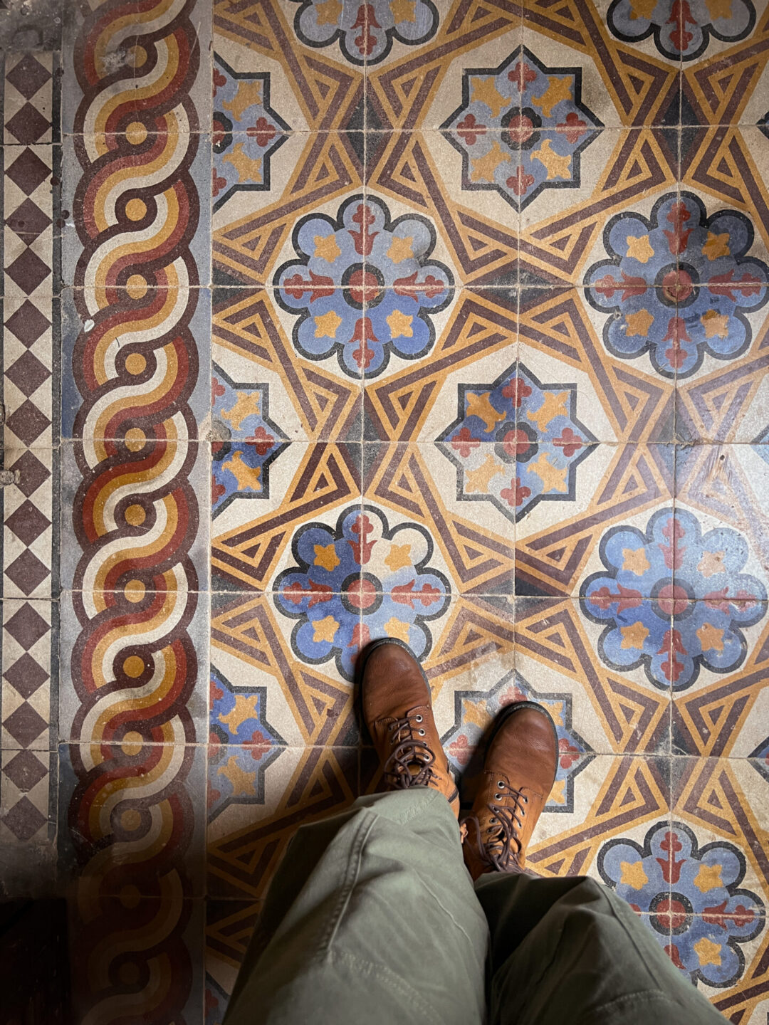 A geometric patterned floor in colors of red, gold, brown and blue inside An Dinh Palace in Hue, Vietnam
