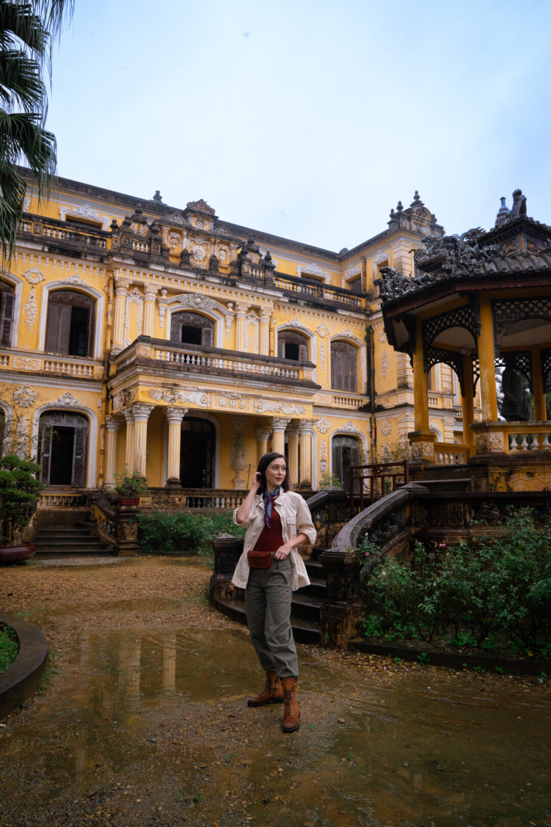 Travel Blogger Jordan Gassner standing outside the yellow European-style An Dinh Palace in Hue, Vietnam
