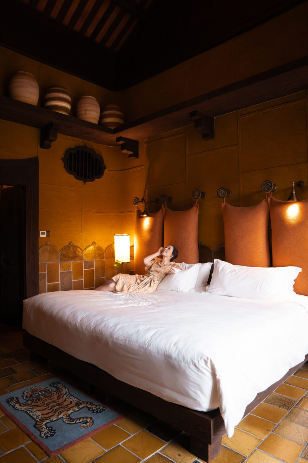 Travel Blogger Jordan Gassner looking up and smiling while lounging on one of the large beds inside a deluxe room at Legacy Yen Tu in Vietnam