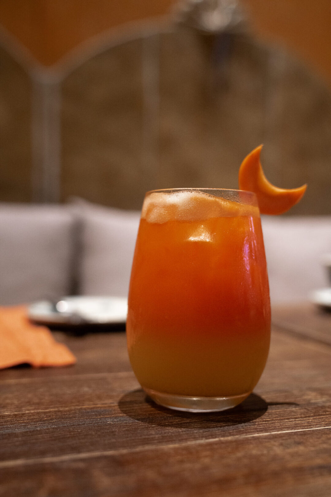 A specialty cocktail with a crescent moon shaped mango slice sitting on the glass from a restaurant inside Legacy Yen Tu resort in Vietnam