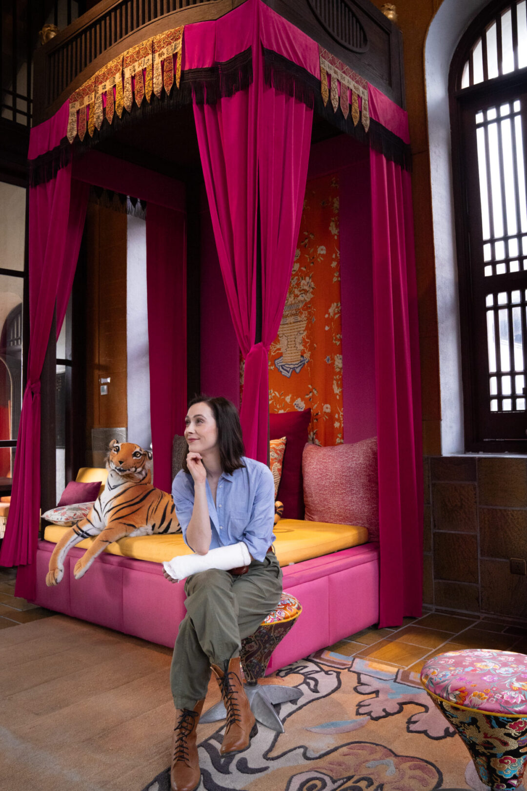 Travel Blogger Jordan Gassner sitting and smiling in front of a chaise lounge with a large stuffed tiger in Legacy Yen Tu - MGallery