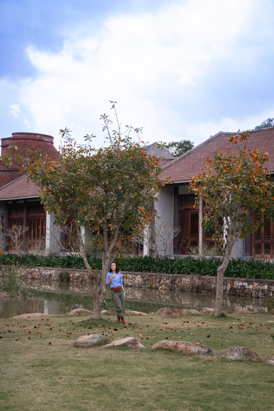 Travel Blogger Jordan Gassner leaning against an orange and green leafed tree outside Legacy Yen Tu in Northern Vietnam