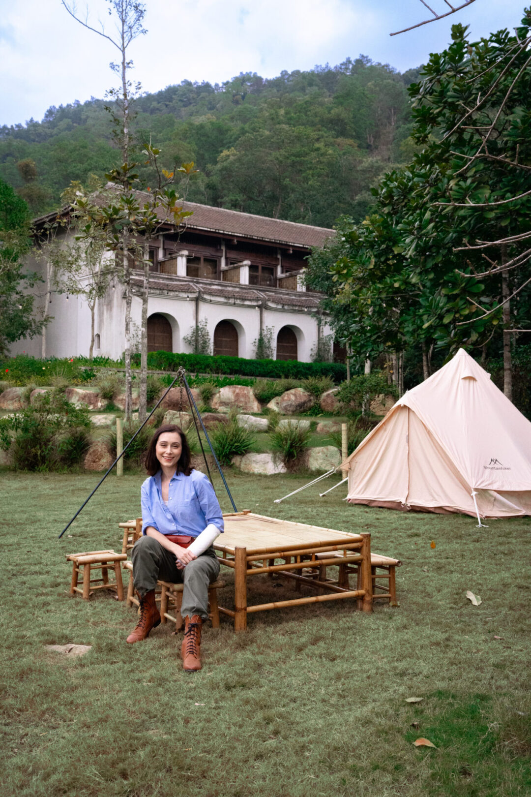 Travel Blogger Jordan Gassner sitting at a wooden bench near a tent outside Legacy Yen Tu Resort in Vietnam