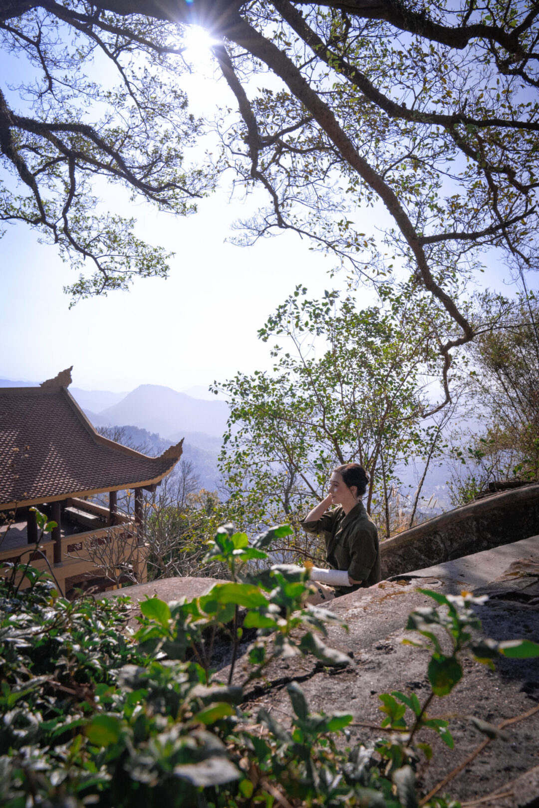 Travel Blogger Jordan Gassner sitting on steps near an 800 year old pagoda on top of Yen Tu Mountain in Vietnam